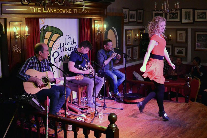 A group playing live music as a woman gets ready to dance at The Irish House Party