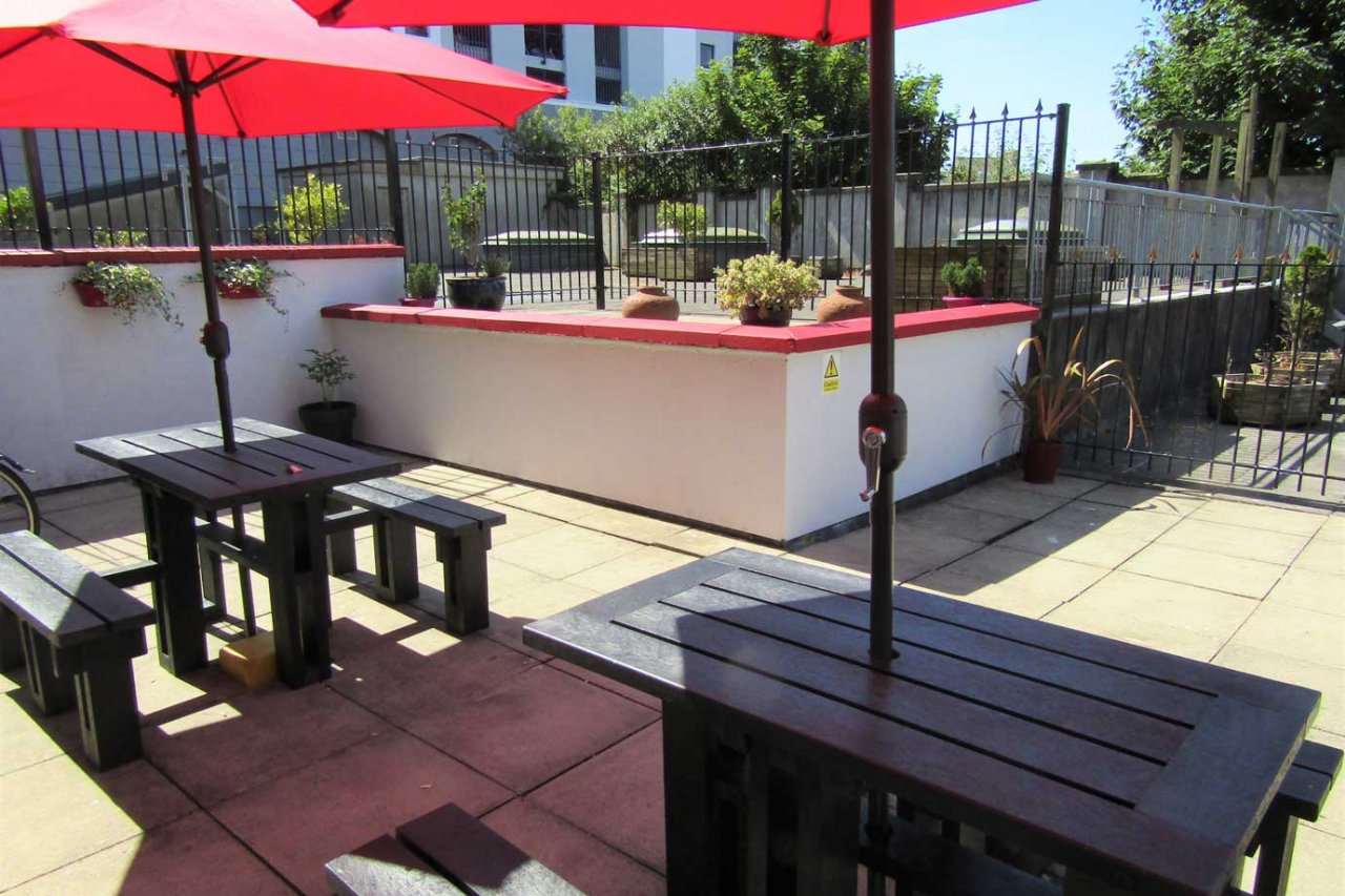 Galway Hostel Patio Area ready for Groups of Backpackers Red Umbrellas Picnic Tables - Hostel Patio Garden