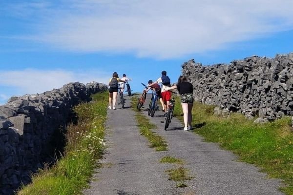 Students walking with their bikes up a hill in the great outdoors on the Aran Islands